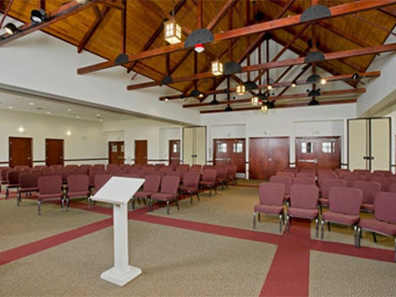 monocacy-hall A spacious room with red chairs, wooden ceiling beams, and a lectern, resembling a conference or meeting hall setting. No people are present.